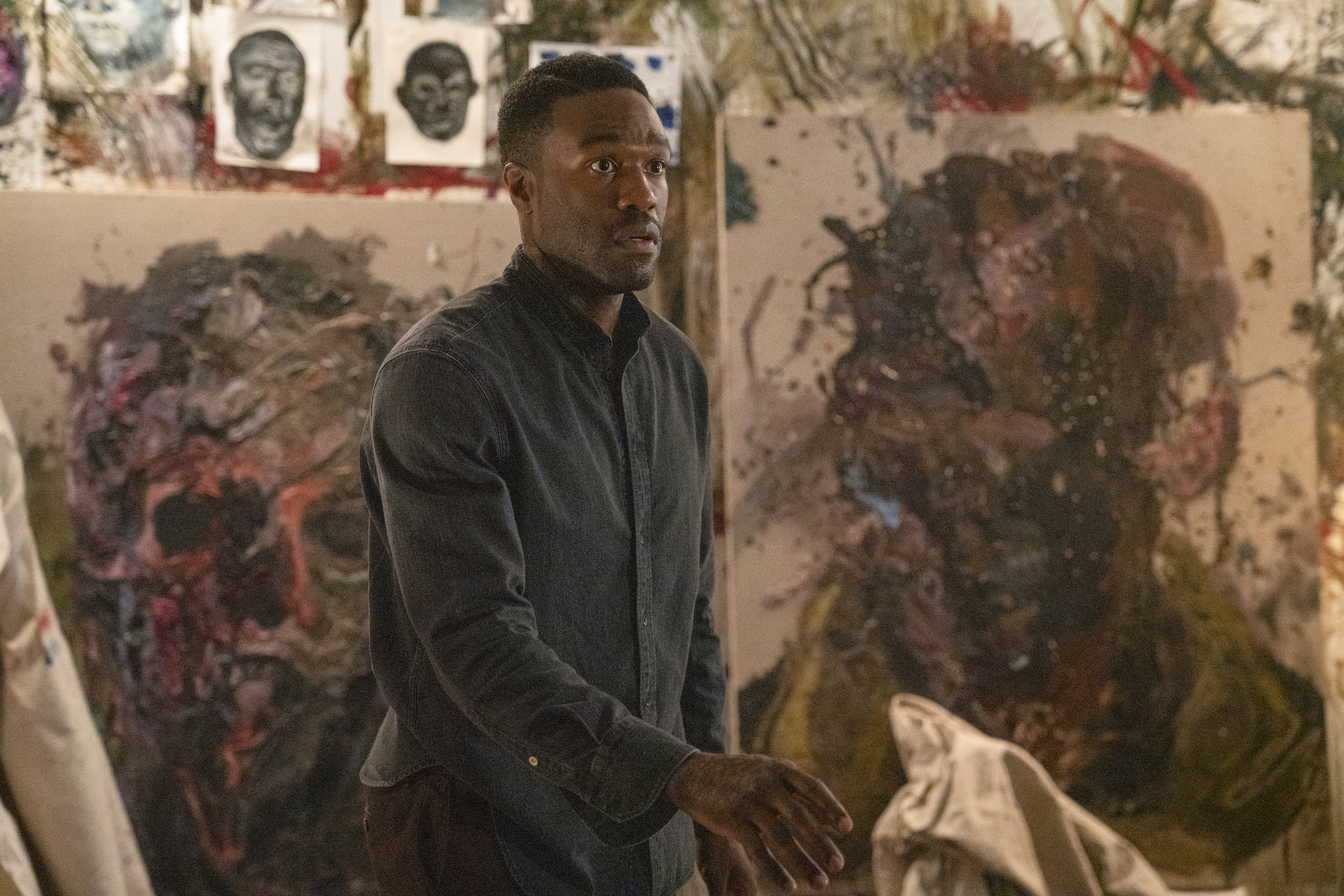 Yahya Abdul-Mateen II in the 2020 film Candyman in front of paintings and drawings.