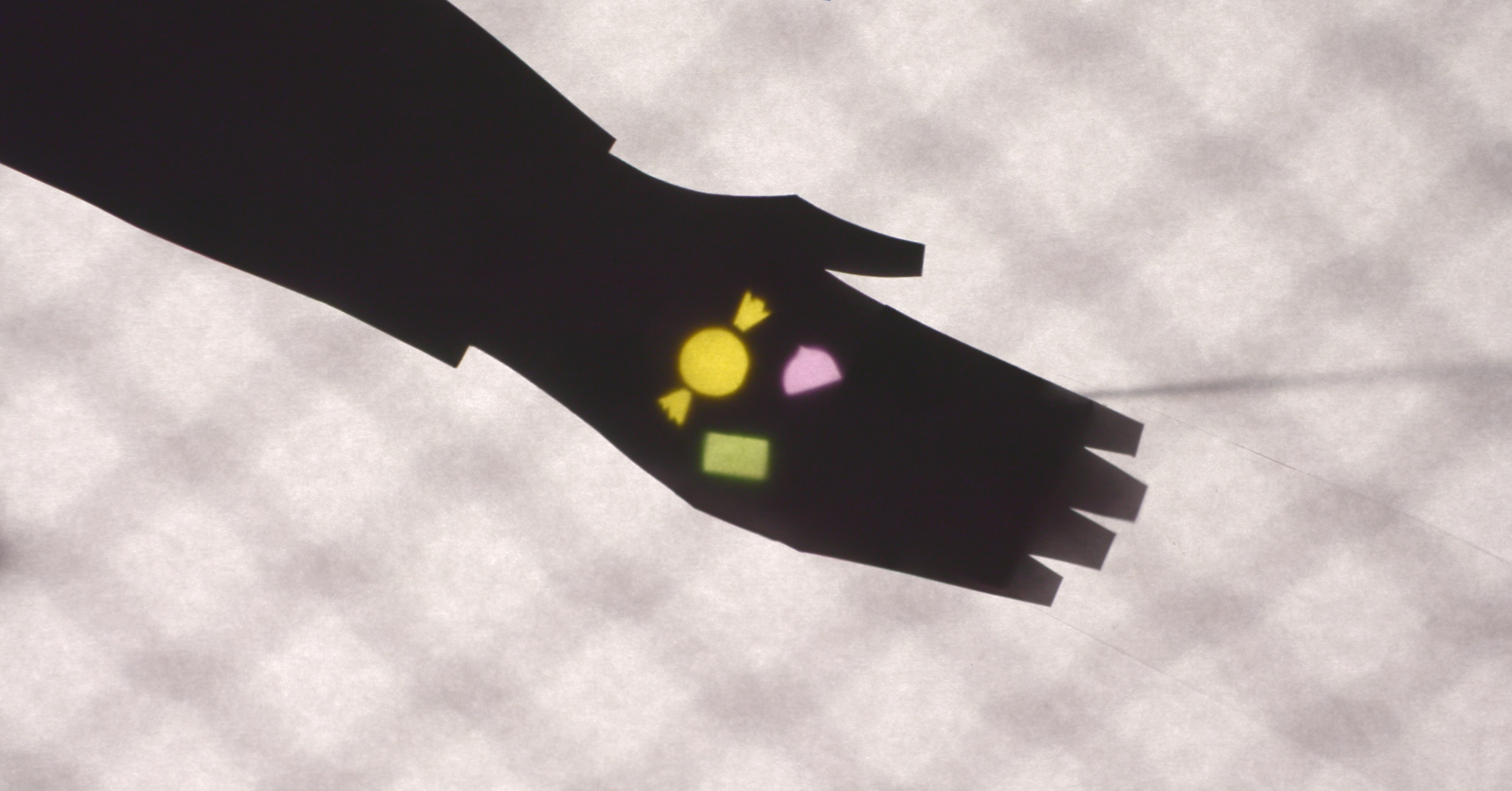 A shadow hand holding colorful candy