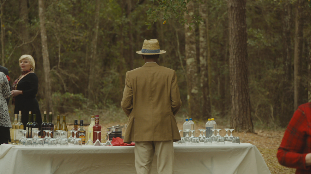 Lakieth Stanfield in the 2017 film GET OUT standing at cocktail table.