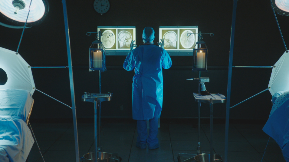 Bradley Whitford in 2017 film GET OUT viewing X-rays in surgery scrubs with hands raised.