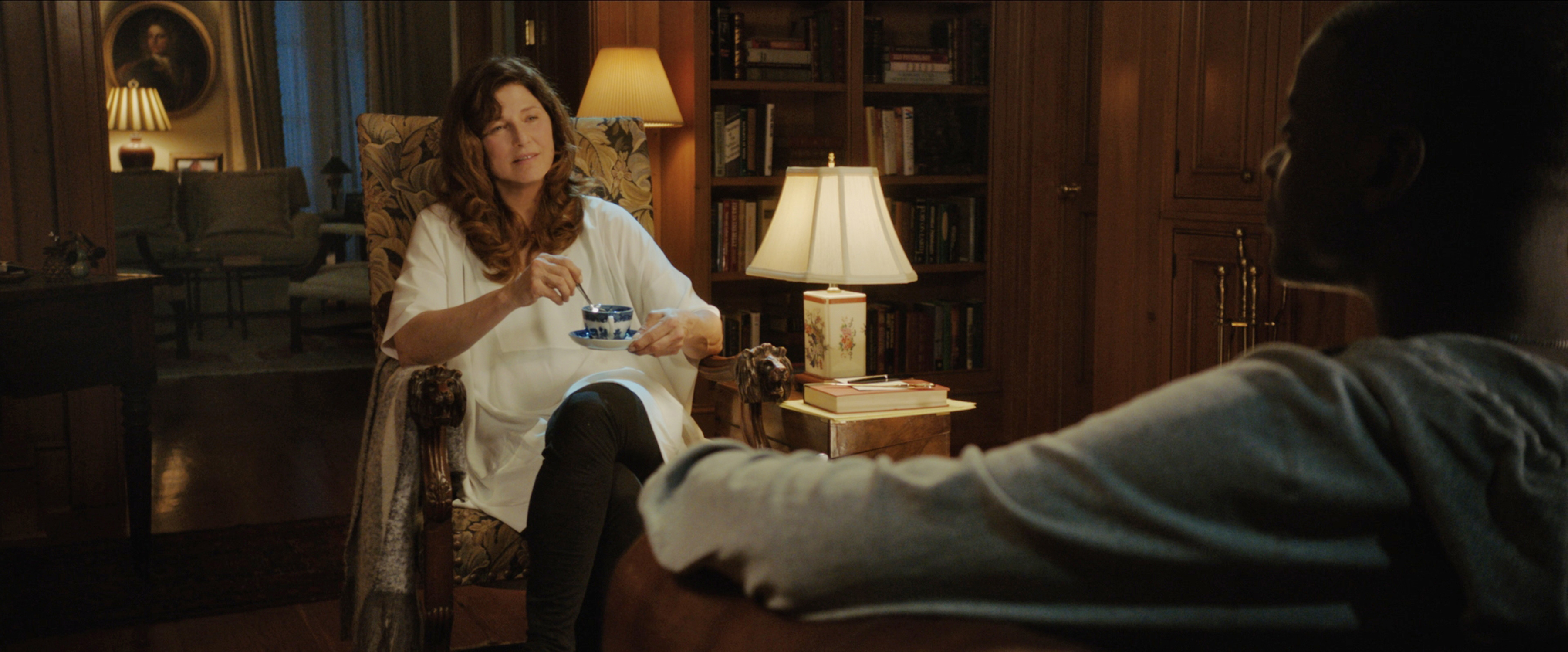 Catherine Keener in 2017 film GET OUT talking to Daniel Kaluuya while sitting and stirring tea.