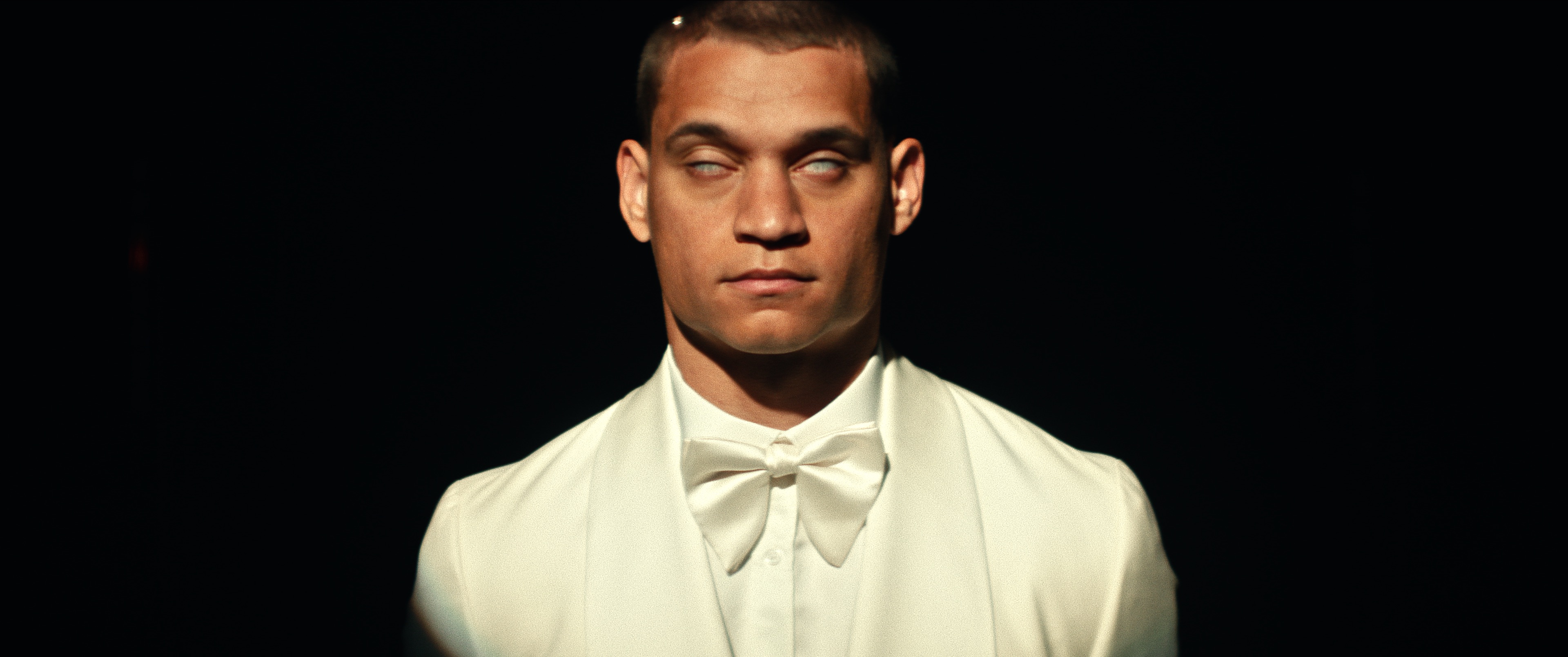 Close up of actor Tyriq Withers in character wearing white tuxedo with his eyes rolled back.