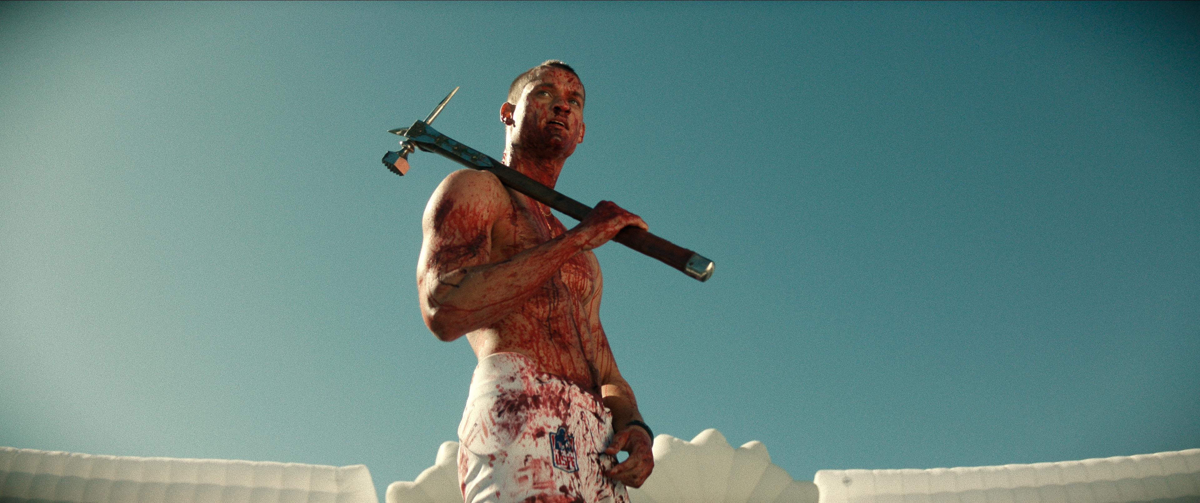 Actor Tyriq Withers in character, sprayed in blood holding an unusual axe.