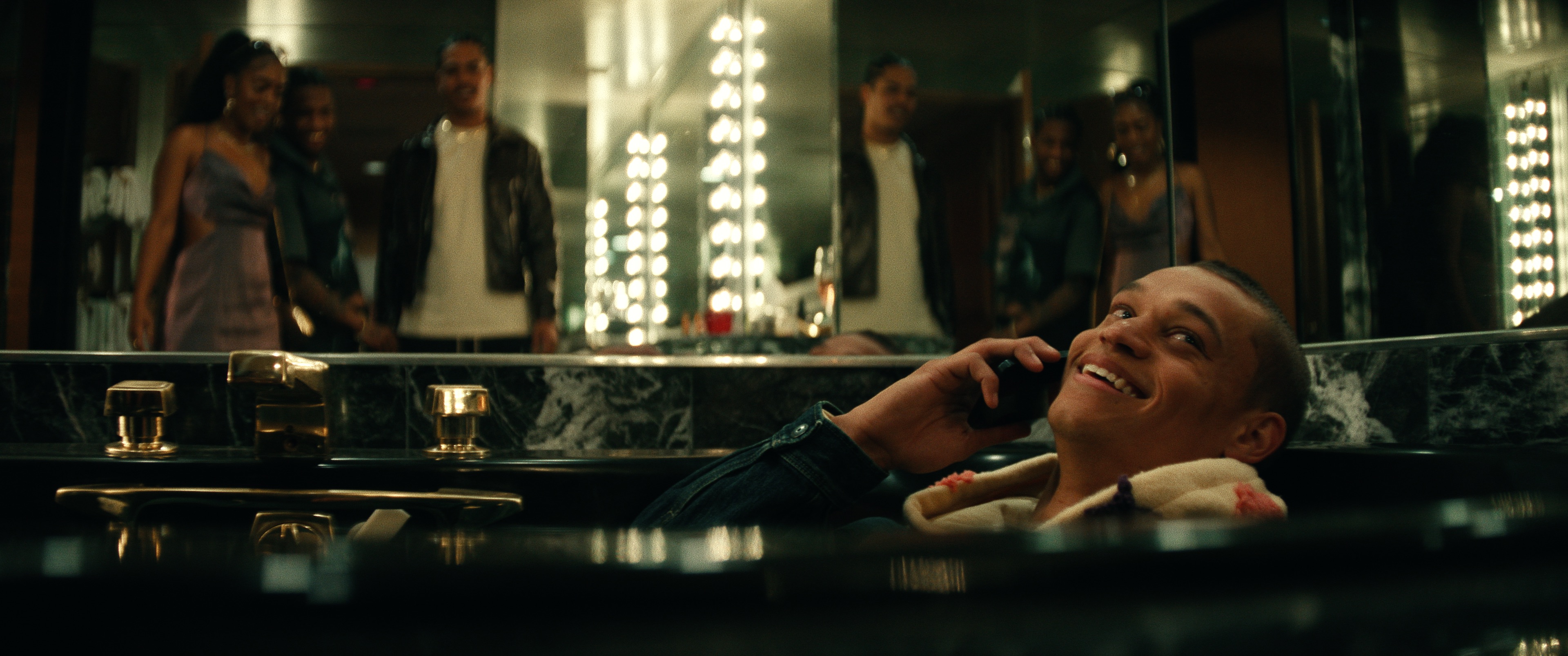 Actor Tyriq Withers in character inside a luxury dressing room on the phone, smiling.