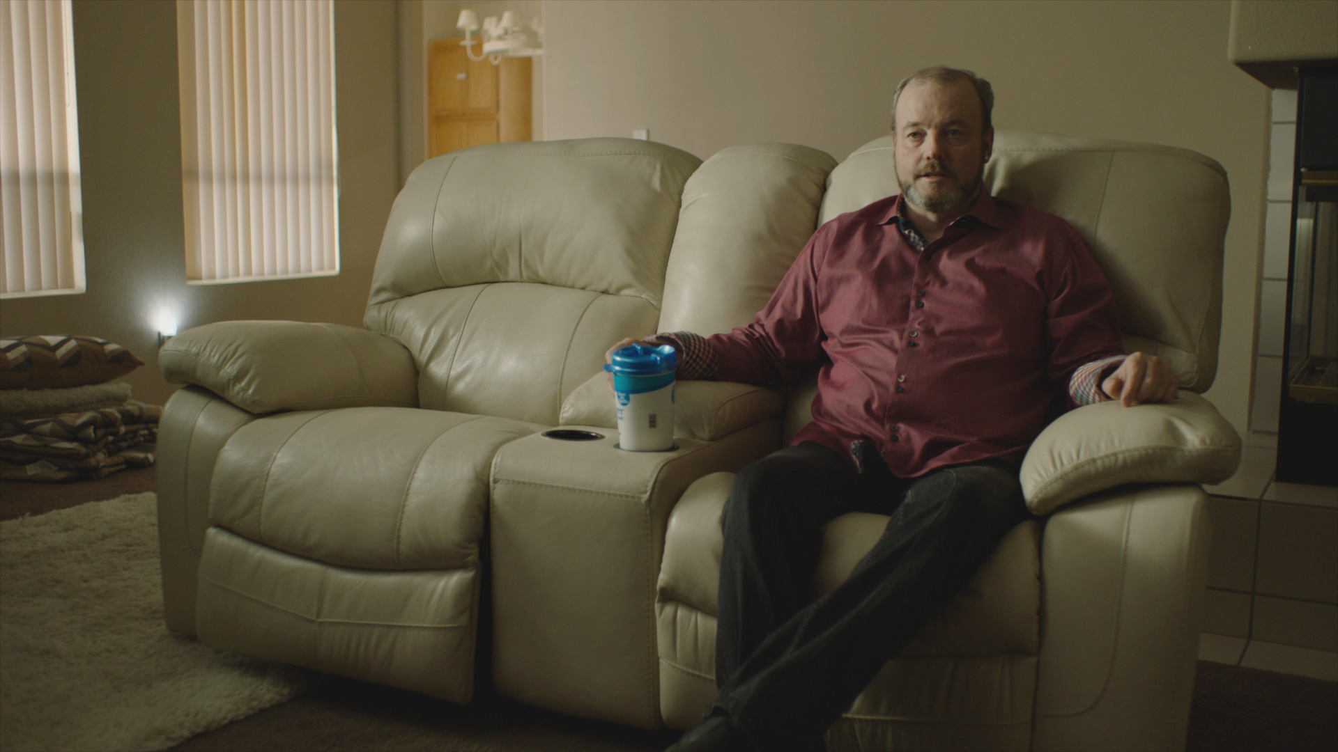 John Wayne Bobbitt in the 2019 documentary series LORENA sitting on a double sofa.