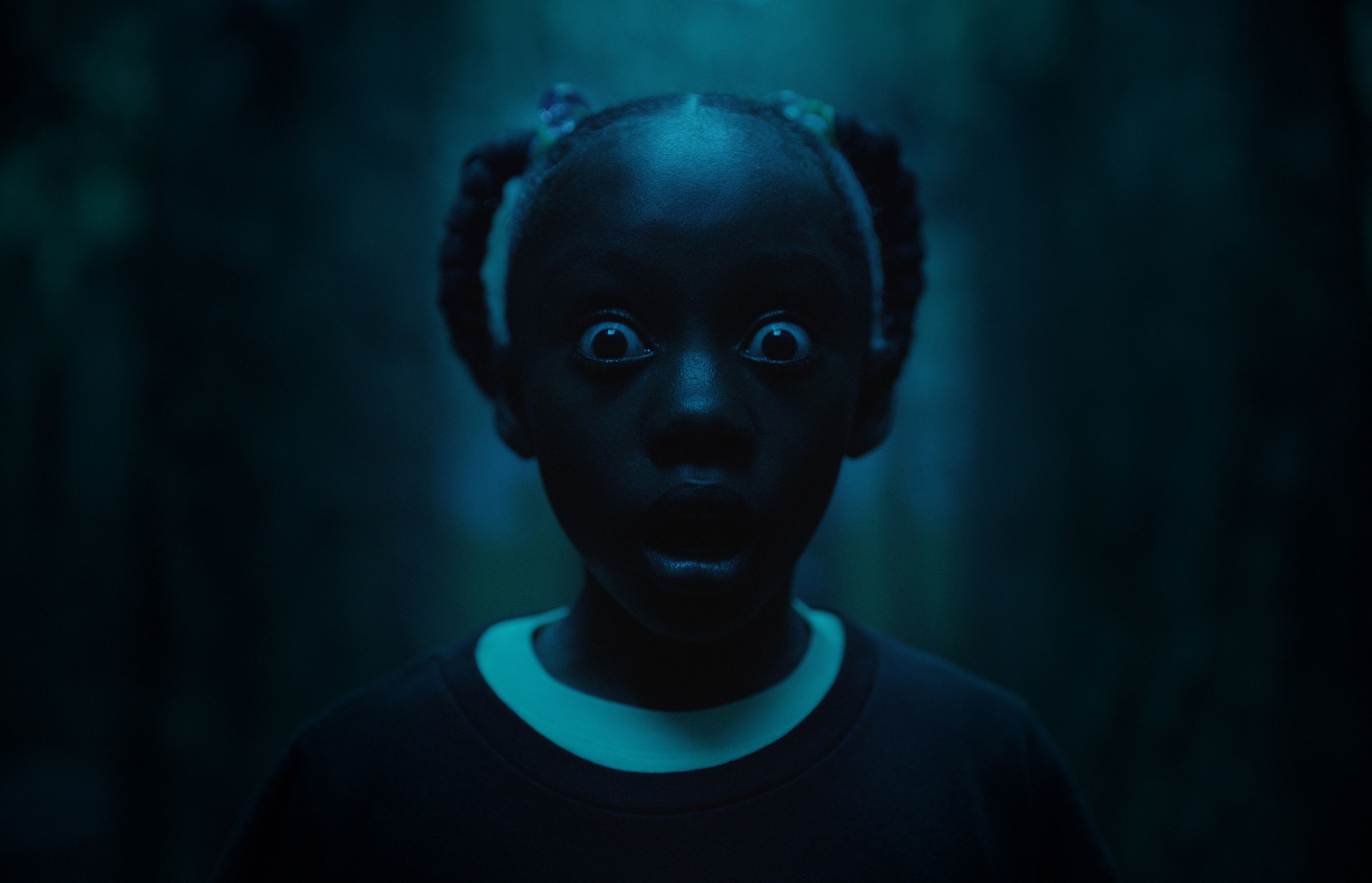 Madison Curry in the 2019 film US standing with eyes wide open and mouth agape.