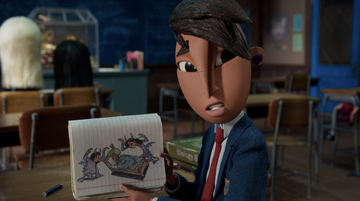 Raul in Wendell and Wild holding a notepad with a drawing of monsters.