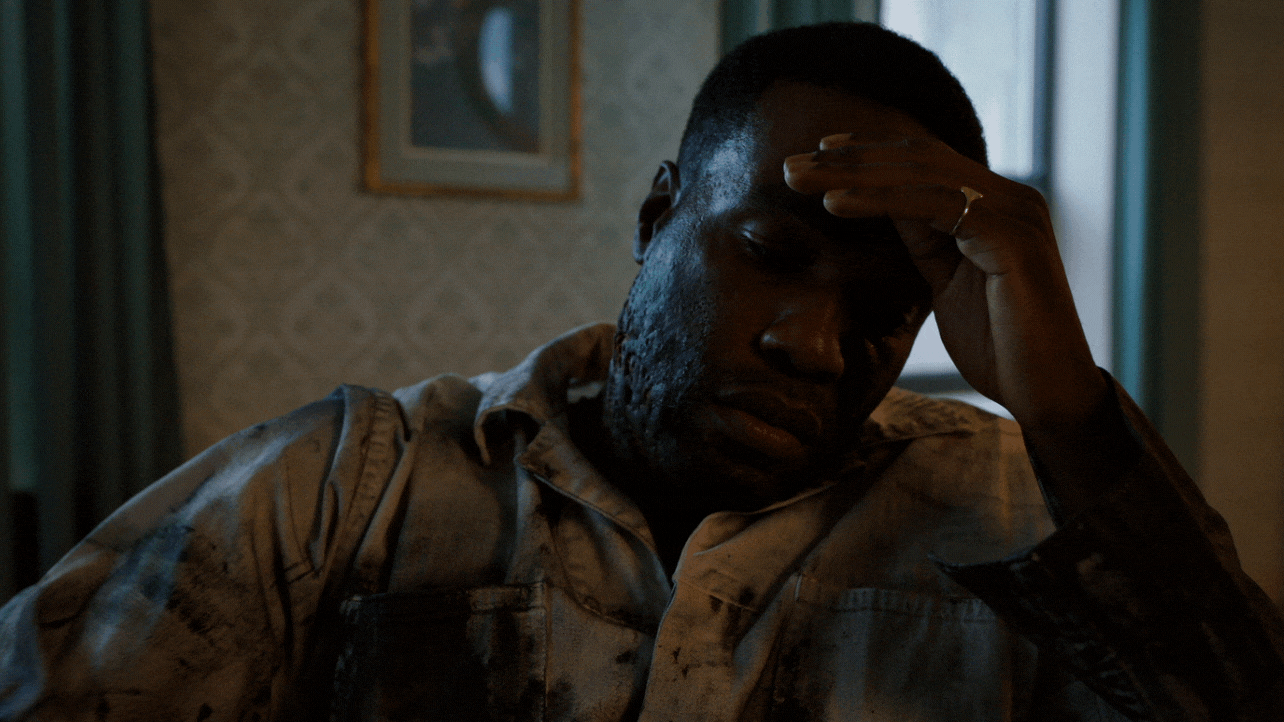 Gif of the main character in Candyman sitting inside of his home with a concerned look and sad look on his face