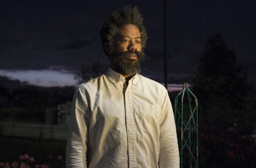Portrait of man standing in front of a dimly lit sky.