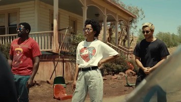 Scene from Nope: Daniel Kaluuya, Keke Palmer, and Brandon Perea standing in front of a disheveled front porch during the day