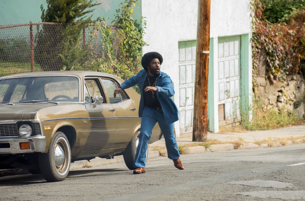 John David Washington in the 2018 film BLACKKKLANSMAN moving past a parked car.