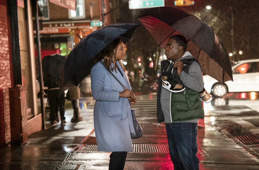 Tiffany Haddish and Tracy Morgan facing each other while holding umbrellas on a sidewalk in Season 1 of THE LAST O.G released in 2018.