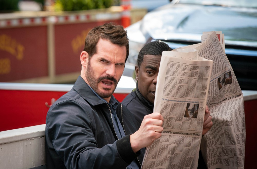 Man looking confused while reading a newspaper.